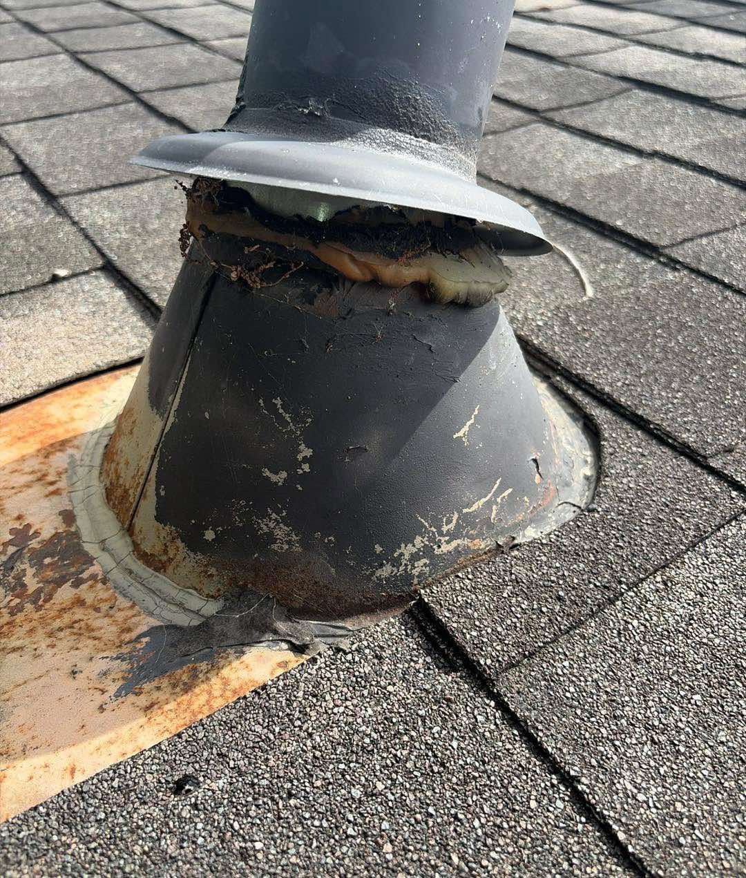 Deteriorated plumbing vent boot with rusted flashing on an asphalt shingle roof